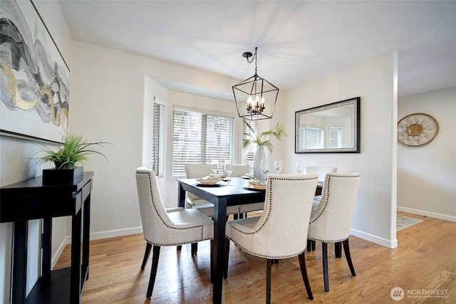 dining room with light wood-type flooring, a chandelier, and baseboards