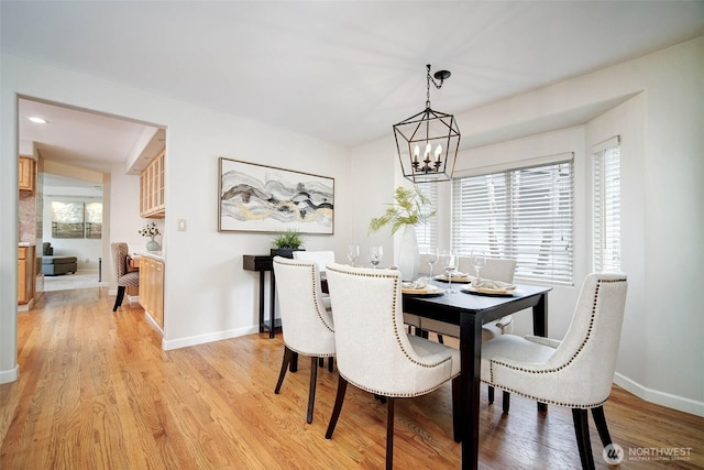 dining space featuring baseboards, light wood finished floors, and a chandelier