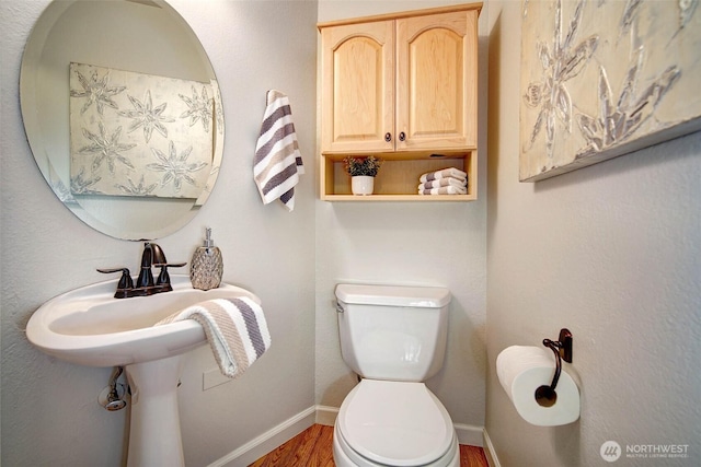bathroom with wood finished floors, baseboards, and toilet