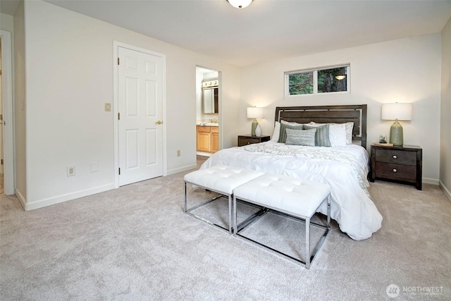 bedroom featuring baseboards, ensuite bath, a sink, and light colored carpet