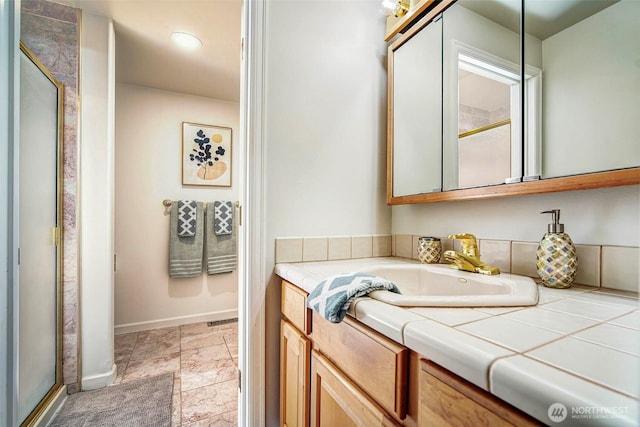 bathroom featuring a shower stall, baseboards, and vanity