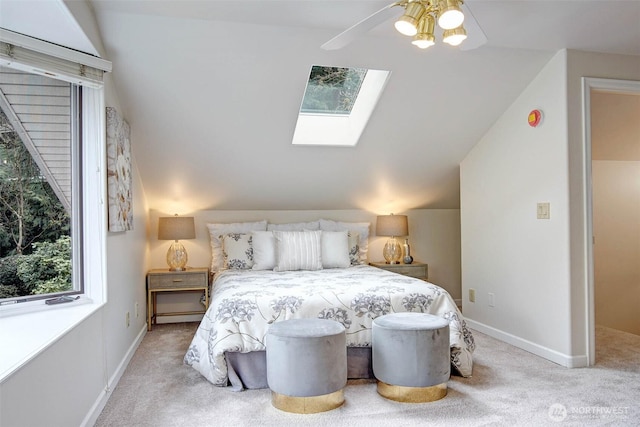 bedroom with ceiling fan, lofted ceiling with skylight, carpet floors, and baseboards