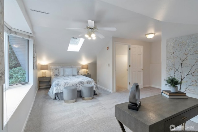 carpeted bedroom featuring baseboards, ceiling fan, visible vents, and vaulted ceiling with skylight