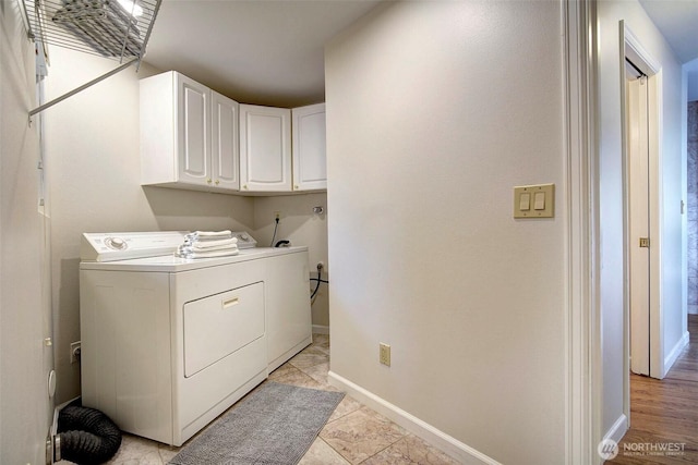 washroom featuring baseboards, separate washer and dryer, and cabinet space