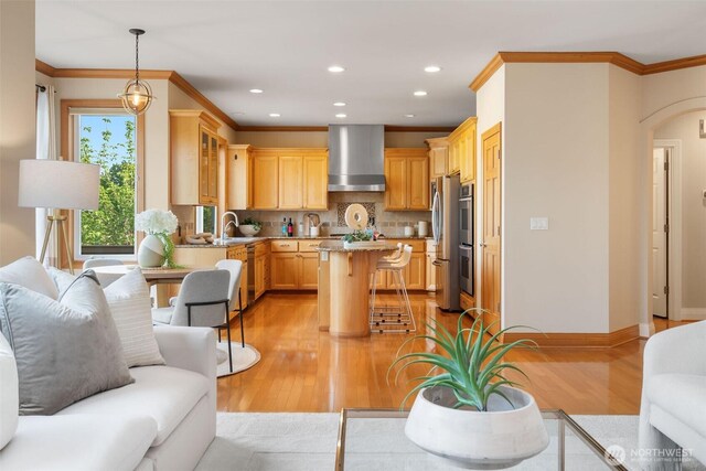 11758 175th Pl NE, Redmond, WA 98052 - kitchen with wall chimney exhaust hood, appliances with stainless steel finishes, light wood finished floors, a kitchen breakfast bar, and ornamental molding