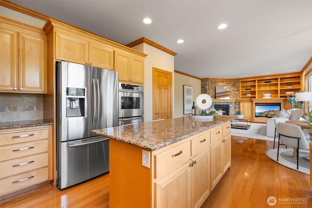 11758 175th Pl NE, Redmond, WA 98052 - kitchen with stainless steel appliances, light brown cabinets, a fireplace, ornamental molding, and a kitchen island