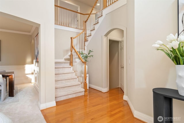 11758 175th Pl NE, Redmond, WA 98052 - stairway featuring arched walkways, wood finished floors, ornamental molding, a towering ceiling, and baseboards