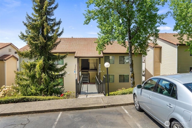 multi unit property with uncovered parking and a tiled roof