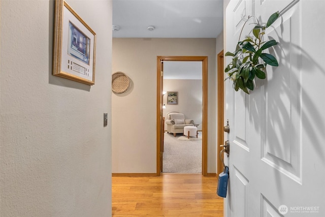 hallway featuring light wood-type flooring and baseboards
