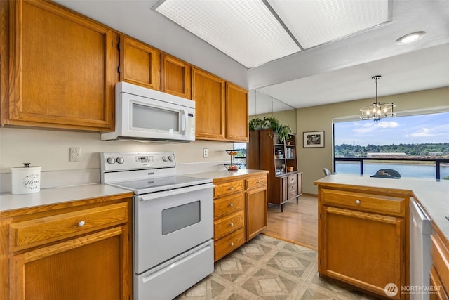 kitchen with white appliances, light countertops, brown cabinets, a chandelier, and decorative light fixtures