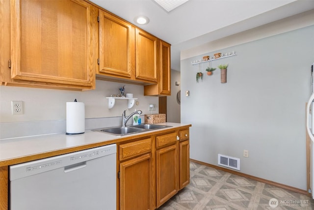 kitchen featuring dishwasher, a sink, light countertops, baseboards, and brown cabinetry