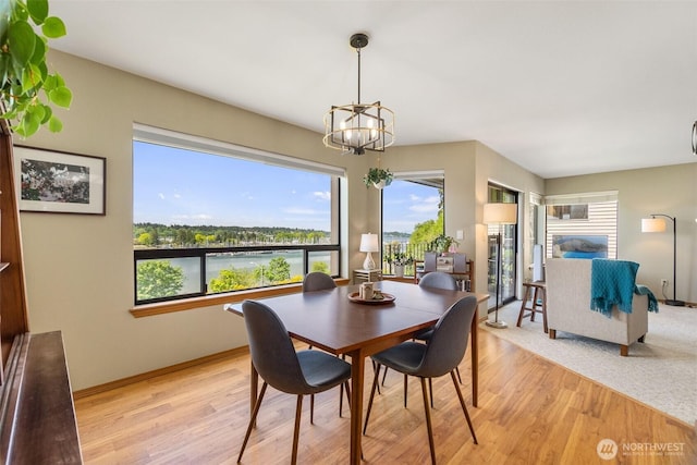 dining area with healthy amount of natural light, light wood-style flooring, a chandelier, and baseboards