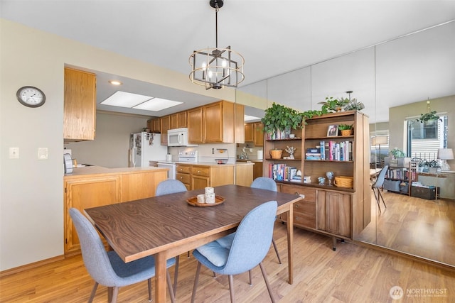 dining area featuring a chandelier, light wood-style flooring, and baseboards