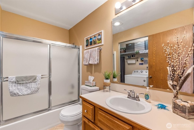full bath with washer / clothes dryer, toilet, vanity, and combined bath / shower with glass door