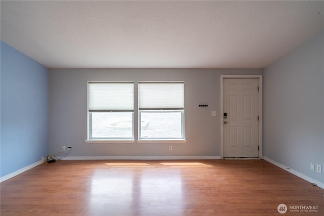 spare room featuring light wood-style floors and baseboards