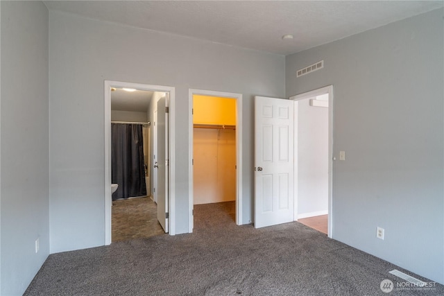 unfurnished bedroom featuring a walk in closet, carpet, and a closet