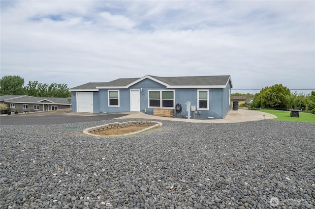 ranch-style house featuring a garage, roof with shingles, and driveway