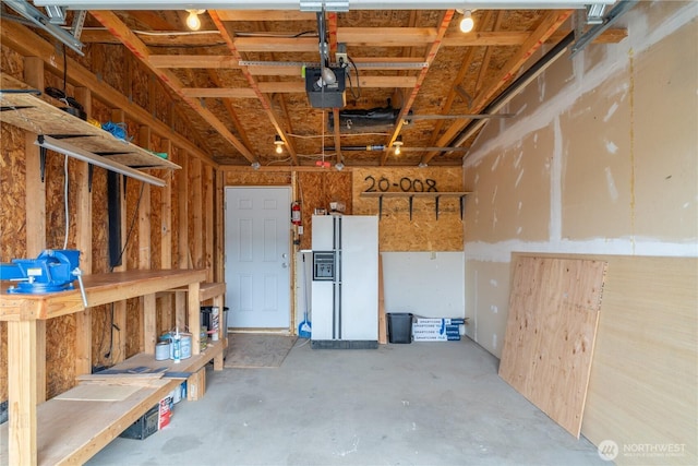 garage with white fridge with ice dispenser, a garage door opener, and a workshop area