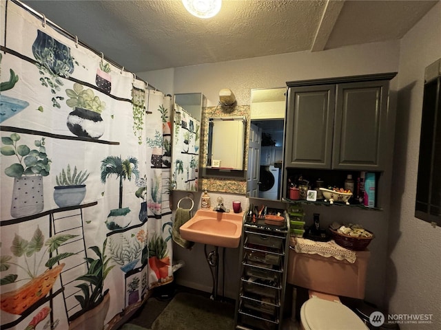 full bath with toilet, a textured ceiling, and a sink