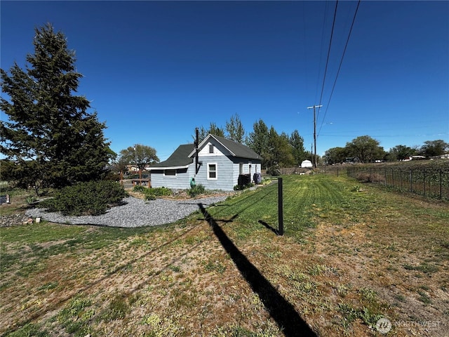 view of side of property featuring fence and a lawn