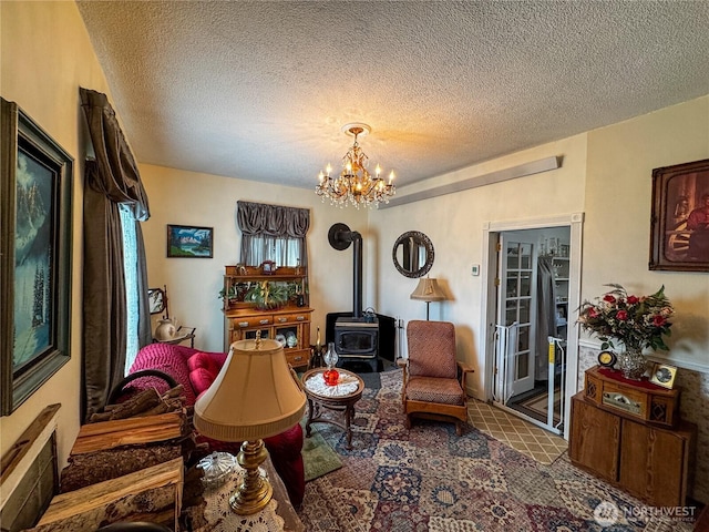 living area with a wood stove, a chandelier, and a textured ceiling