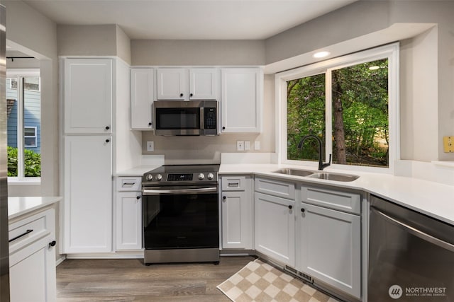 kitchen featuring appliances with stainless steel finishes, a sink, light countertops, and white cabinets