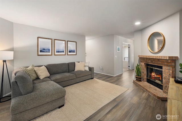 living room featuring wood finished floors, recessed lighting, baseboards, and a brick fireplace