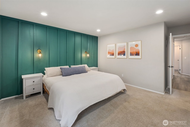 bedroom with recessed lighting, baseboards, a decorative wall, and light colored carpet