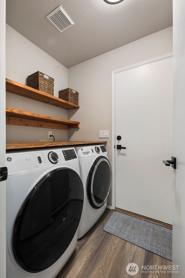 washroom with washer and dryer, dark wood-type flooring, a textured ceiling, and baseboards
