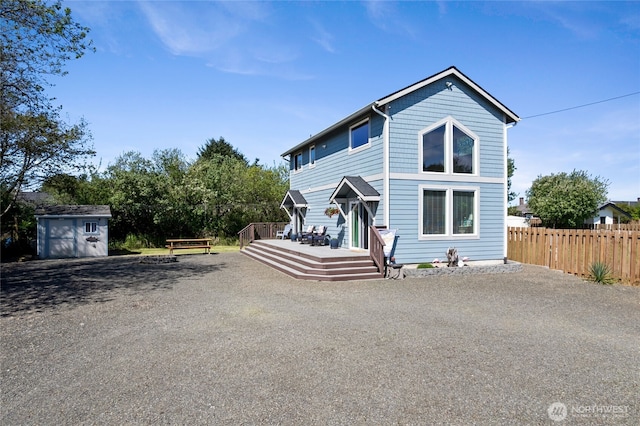 view of front facade with fence, a wooden deck, a storage shed, and an outdoor structure