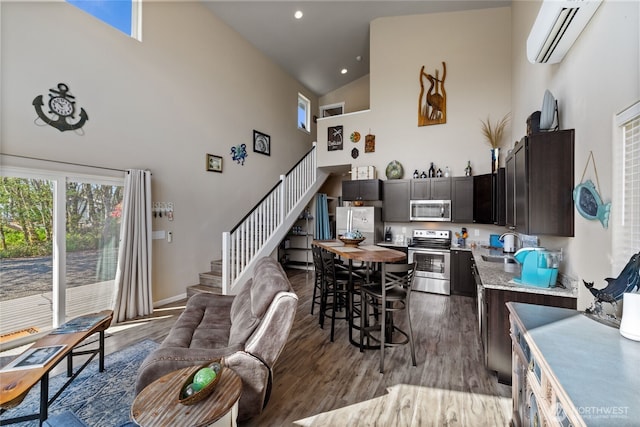 dining room with high vaulted ceiling, an AC wall unit, stairs, dark wood-style flooring, and recessed lighting