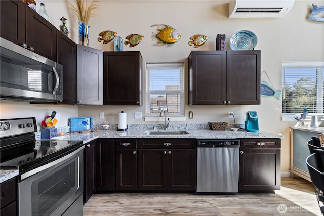 kitchen with appliances with stainless steel finishes, a sink, an AC wall unit, and plenty of natural light