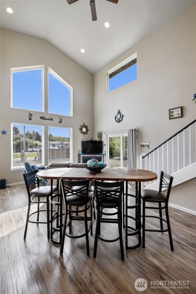 dining space with high vaulted ceiling, wood finished floors, a ceiling fan, stairway, and recessed lighting