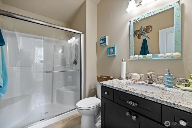 full bathroom featuring toilet, a stall shower, vanity, and tile patterned floors
