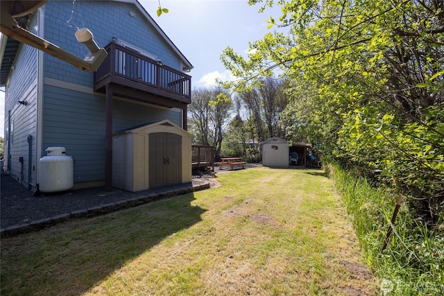 view of grassy yard with a shed, a balcony, and an outbuilding