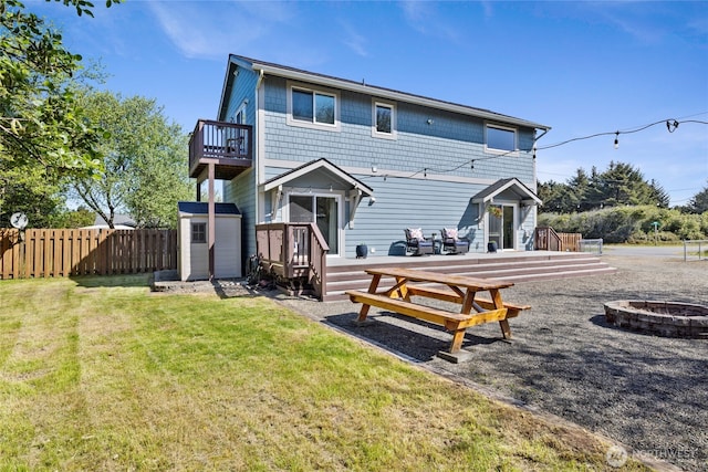 back of house featuring an outdoor fire pit, a storage unit, a deck, and an outbuilding