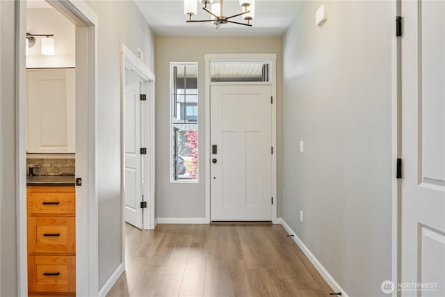 entrance foyer featuring a chandelier, light wood-type flooring, and baseboards