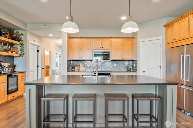 kitchen featuring stainless steel appliances, dark countertops, tasteful backsplash, wine cooler, and a kitchen bar
