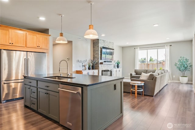 kitchen featuring a sink, appliances with stainless steel finishes, dark countertops, dark wood finished floors, and recessed lighting