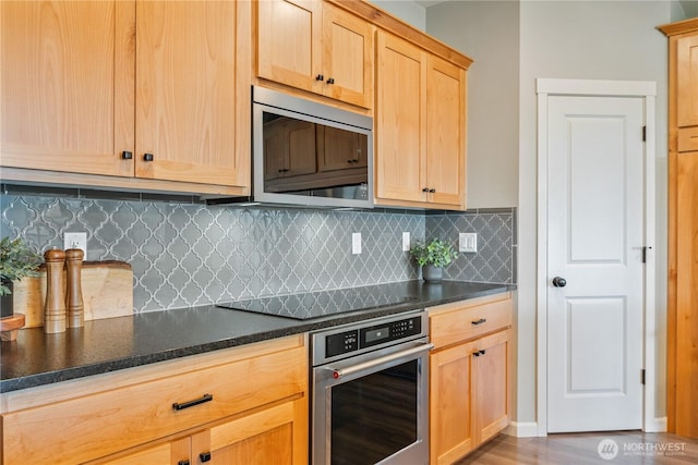 kitchen with appliances with stainless steel finishes, light brown cabinets, dark countertops, and decorative backsplash