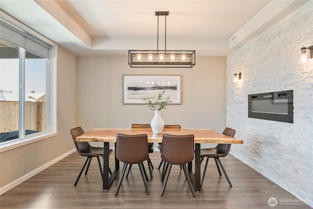 dining area featuring wood finished floors, baseboards, and a tray ceiling