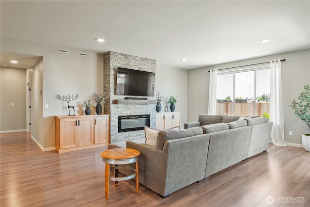 living area with wood finished floors, recessed lighting, baseboards, and a fireplace