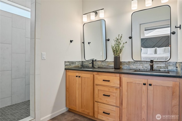 full bathroom with double vanity, baseboards, and tiled shower