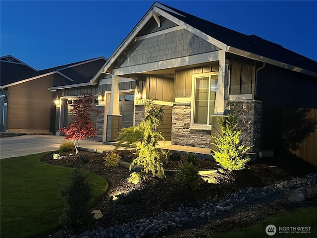 view of front of home featuring board and batten siding, stone siding, and concrete driveway