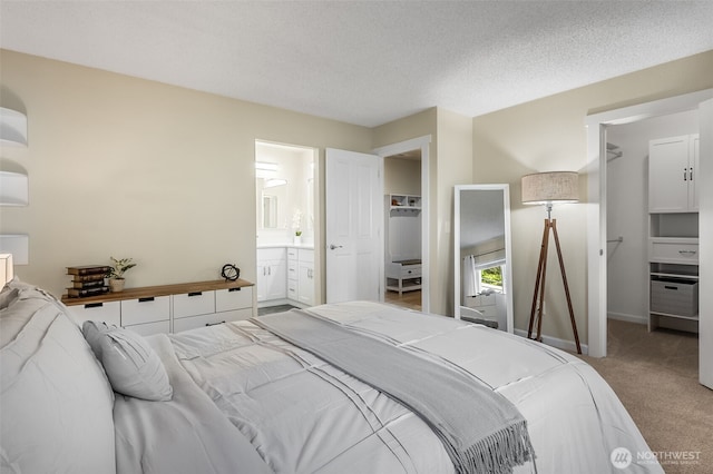 bedroom with a spacious closet, light colored carpet, a closet, and baseboards