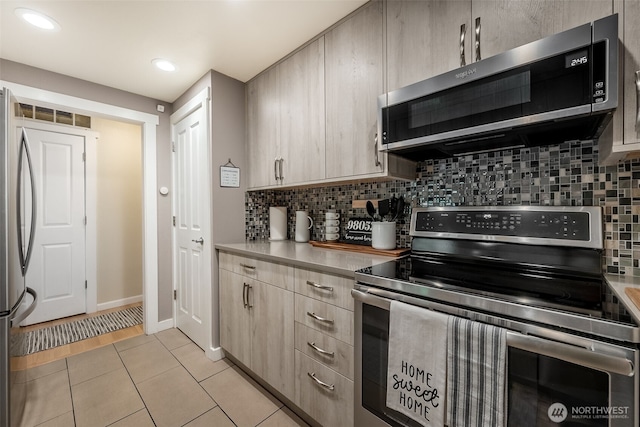 kitchen featuring stainless steel appliances, light brown cabinets, tasteful backsplash, light countertops, and light tile patterned floors