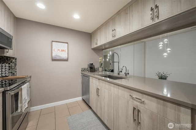kitchen with stainless steel appliances, light brown cabinets, a sink, and light tile patterned floors