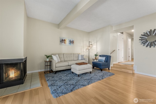 living room with wood finished floors, a multi sided fireplace, beam ceiling, and baseboards