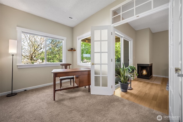carpeted office space with vaulted ceiling, baseboards, a multi sided fireplace, and french doors