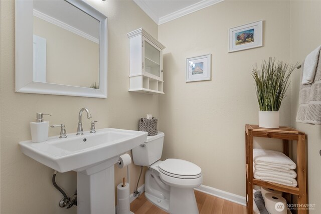 bathroom featuring wood finished floors, crown molding, toilet, and baseboards